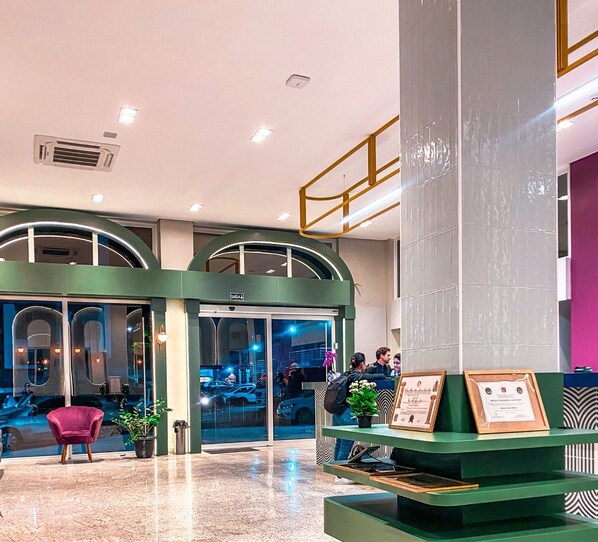Enter a stylish lobby with a curved glass entrance, comfortable seating area, and a reception desk.