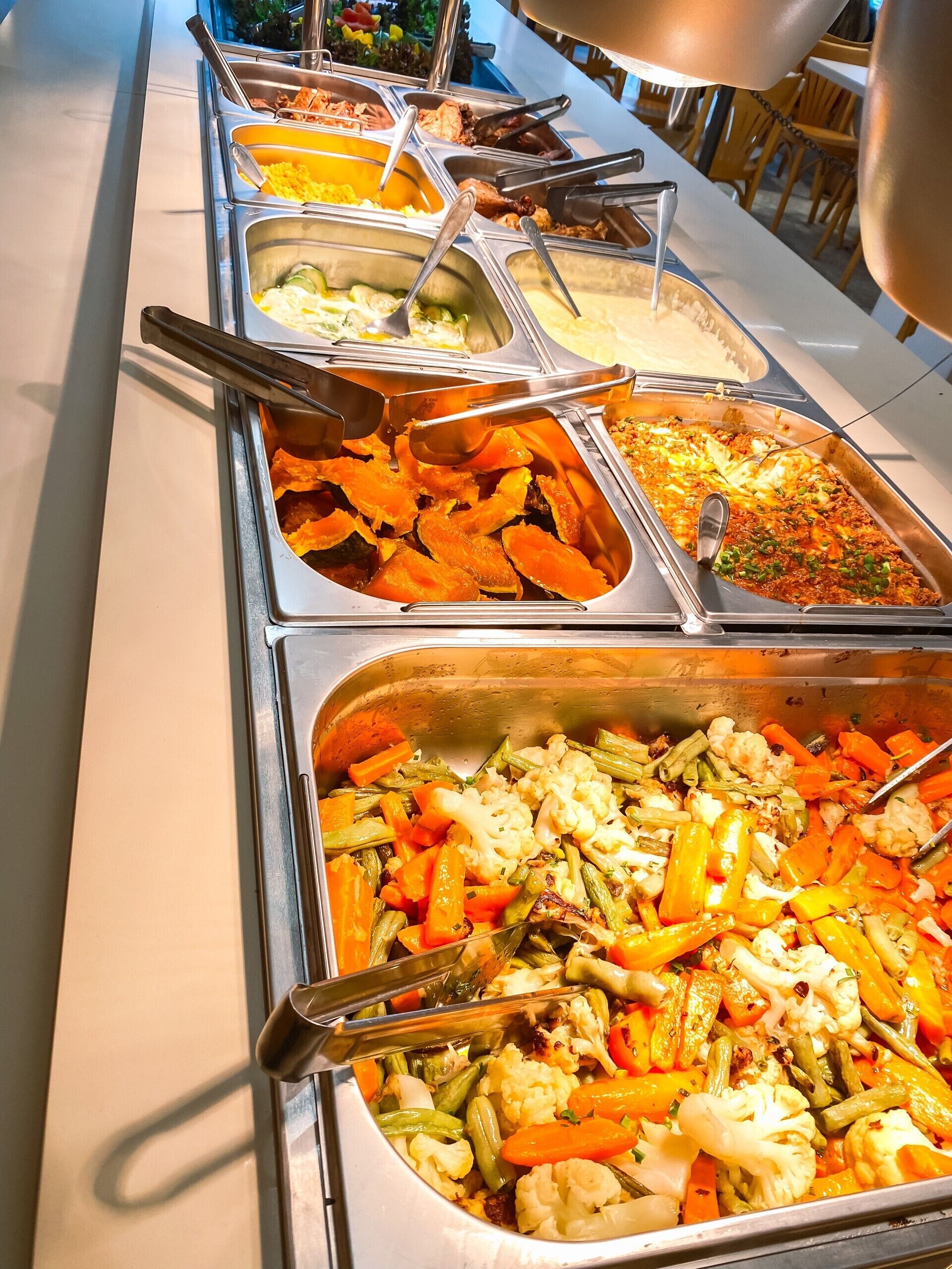 Un buffet con diverse opzioni gastronomiche, tra cui insalate, carni e verdure miste.