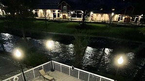 Une piscine à bord incurvé, entourée d’une balustrade blanche, avec une maison visible au loin.