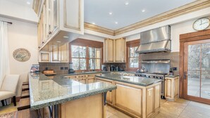 A spacious kitchen with granite countertops, wooden cabinets, and a large island.