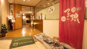 A hotel lobby with a reception desk, a green mat indicating the restaurant, and a decorative lantern display.