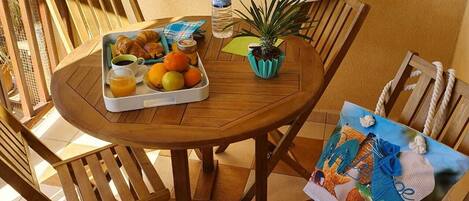 A wooden round table with a tray of fruits and a water bottle.
