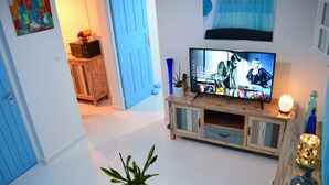 Ein Wohnzimmer mit Fernseher, Holzschrank und einer Topfpflanze.
