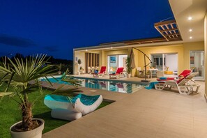 A modern house with a swimming pool, outdoor seating, and a patio area.