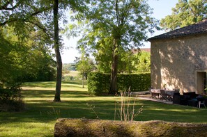 A stone building with a patio area, surrounded by a well-maintained lawn and trees. - Charming rural double cottages - private pool and park (Montreal du Gers)