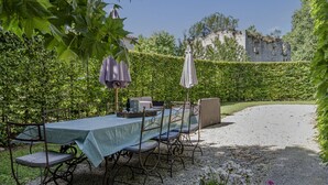 Une table dressée à l’extérieur, avec une nappe, des chaises et des parasols.