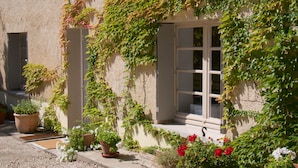 Un bâtiment doté d’une fenêtre et d’une porte, entouré de plantes et de fleurs en pot.