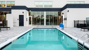 A modern hotel with a swimming pool, a covered entrance, and a clear view of the surrounding area. - Aloft by Marriott Savannah Airport (Pooler)