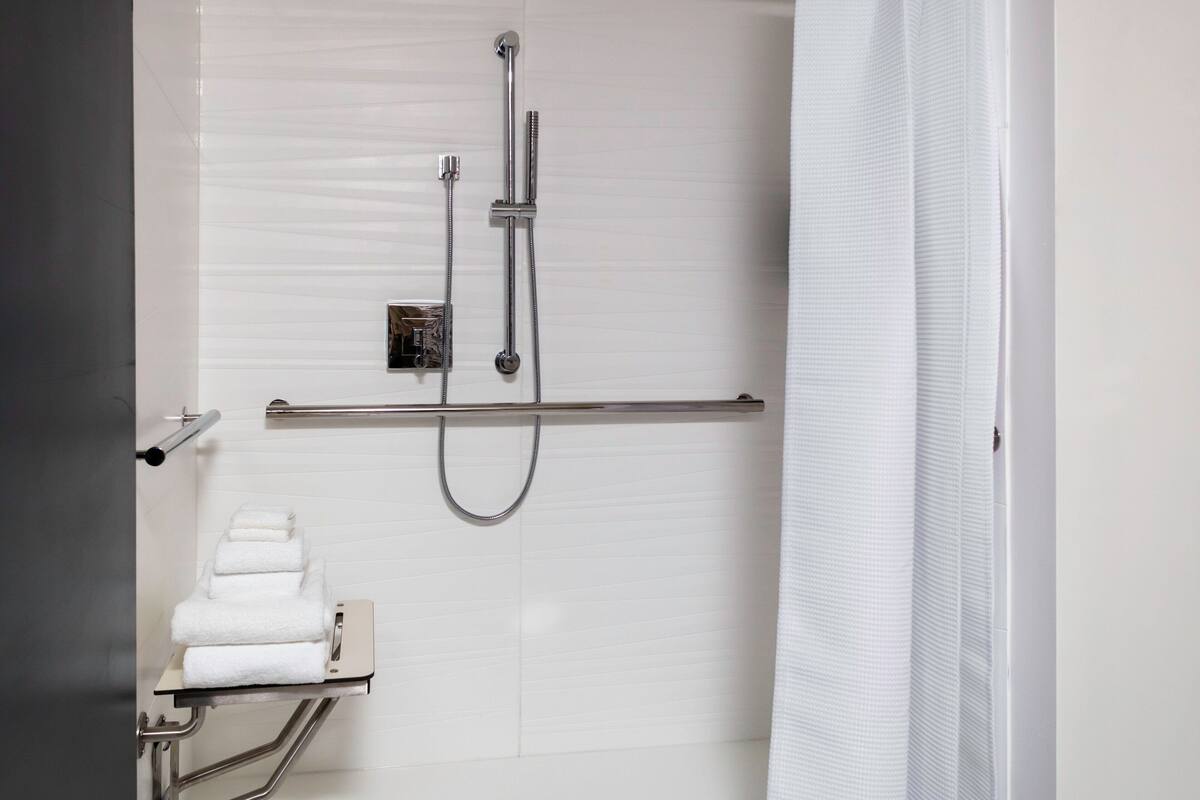 Een moderne badkamer met een douche, een handdoekhouder en een handgreep.