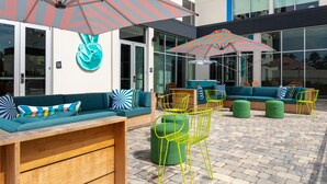 An outdoor seating area with cushioned sofas, chairs, and a wooden bench. - Aloft by Marriott Savannah Airport (Pooler)