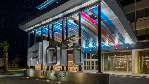 A modern hotel with a large illuminated 'HOTELS' sign, large windows, and a contemporary design. - Aloft by Marriott Savannah Airport (Pooler)