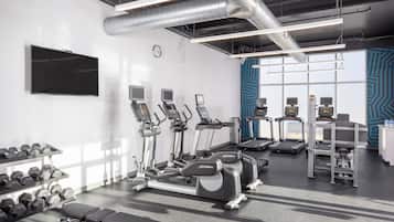 A gym with treadmills, elliptical machines, and dumbbells.