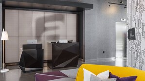 Una zona de recepción moderna con un mostrador, un sofá amarillo y una pared decorada.