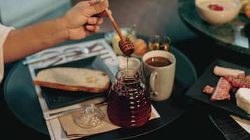 A tray with a glass of honey, a cup of coffee, slices of bread, and a plate of cured meats.
