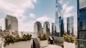 Un edifici alt amb façana de vidre modern, envoltat d'altres gratacels i un cel serè.
