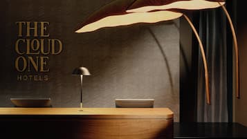 A reception desk with a modern lamp, a wooden counter, and a patterned wall.