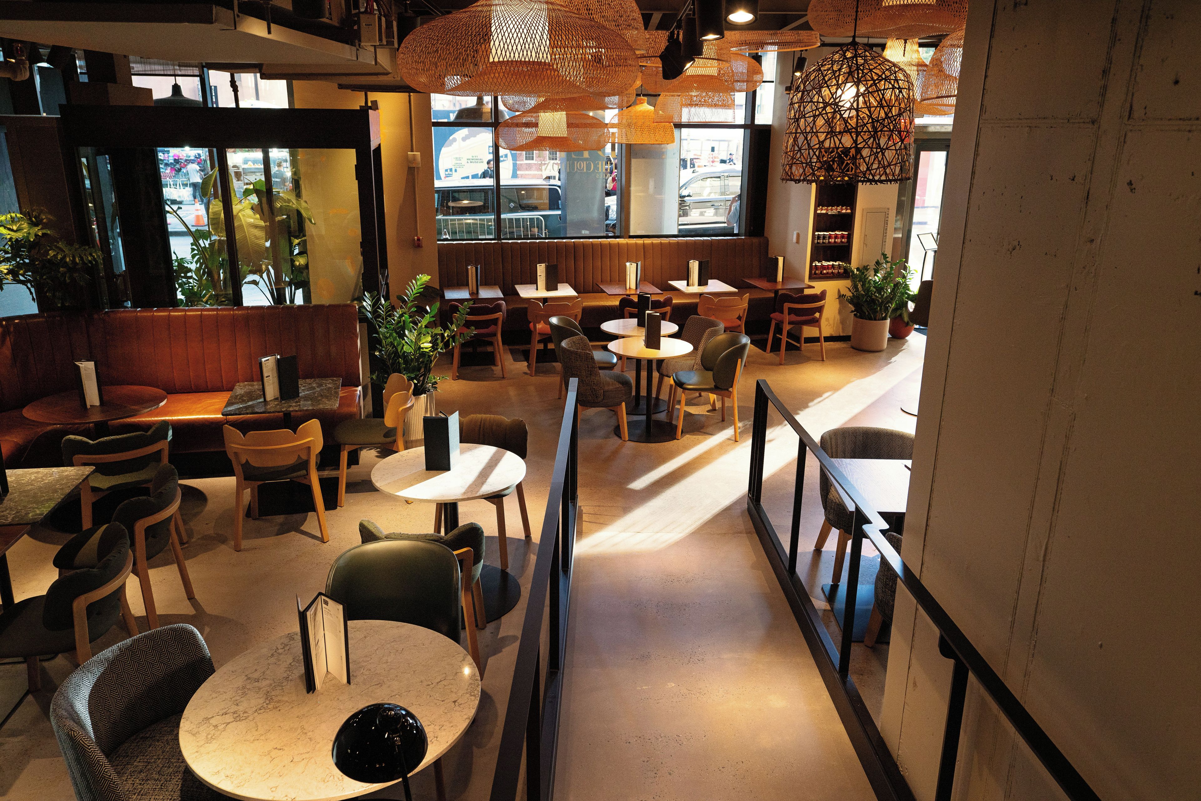 En restauranginteriör med avskilda sittplatser, bord och hängande lampor av rotting.