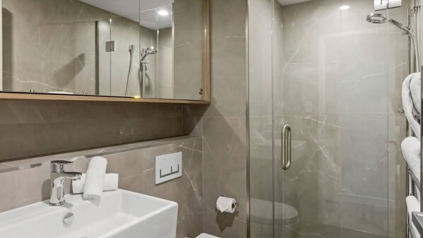 A modern bathroom with a glass-enclosed shower, a sink with a mirror above it, and a towel rack.