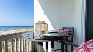 A balcony with a table, a wicker basket, and a glass. The balcony overlooks a beach with sand and the ocean. - Stunning Gulf-Front/Balcony Views + Hot Tub/Top-Rated 10/10/Pensacola Beach (Pensacola Beach)