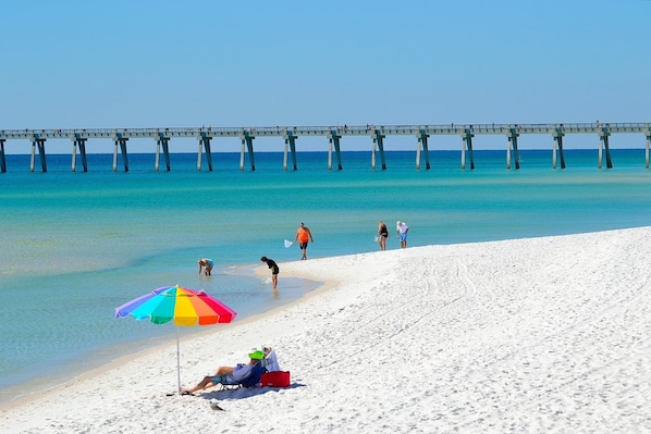 Guests can enjoy a serene beach experience with a pier stretching into the calm sea.