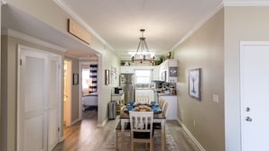 A hallway leading to a dining area with a chandelier, a kitchen with cabinets, and a door with a sign. - Stunning Gulf-Front/Balcony Views + Hot Tub/Top-Rated 10/10/Pensacola Beach (Pensacola Beach)