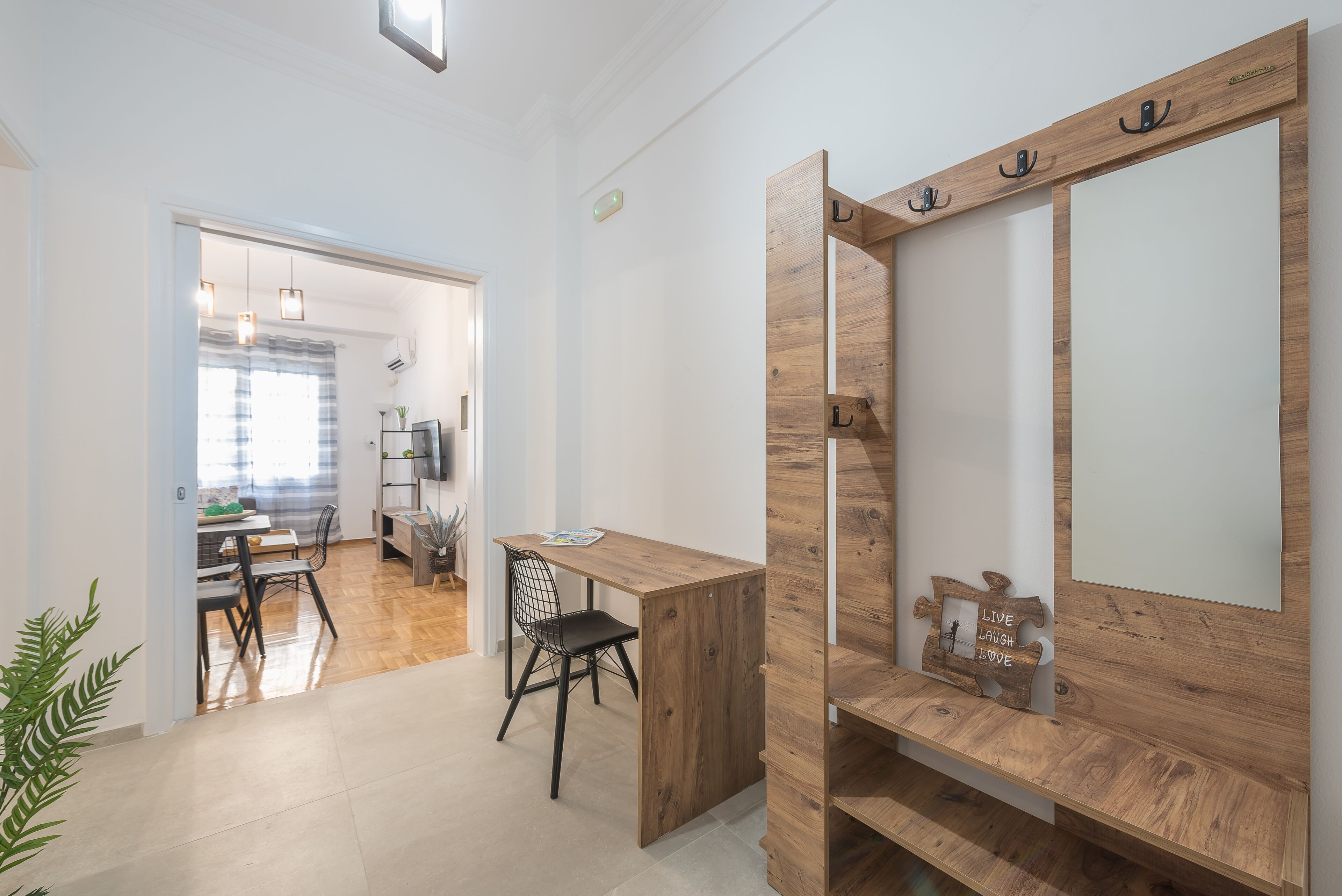 Een modern interieur met een houten bureau en stoel, een kapstok en een spiegel.