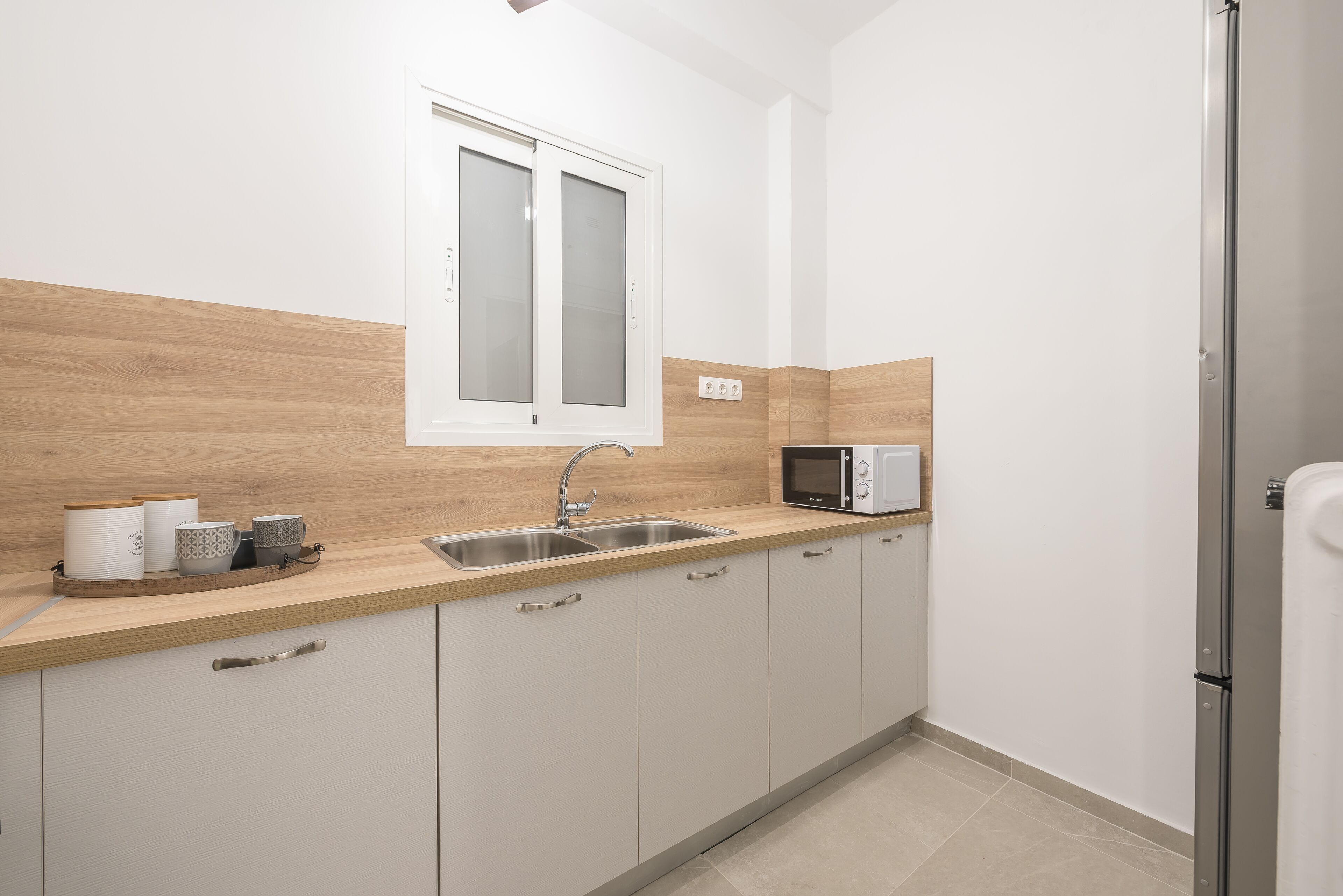 Una cocina moderna con encimera de madera, pileta de acero inoxidable y microondas integrado.