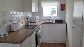 A compact kitchen with white cabinets, a wooden countertop, a microwave, a toaster, and a sink.