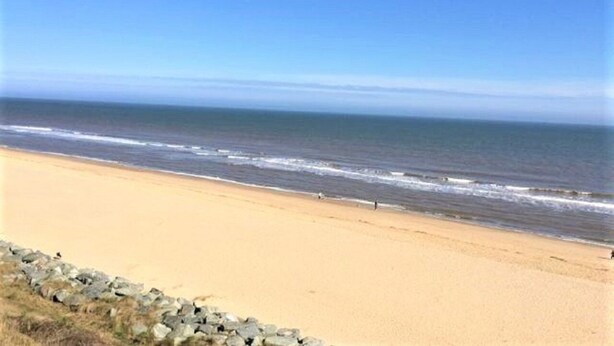 A beach with a clear sky and calm sea.