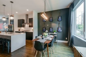 A modern kitchen with a central island, pendant lighting, and a dining area with a table set for four.