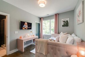 Quarto moderno com cama, escrivaninha, televisão e janela com cortinas.