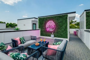 A rooftop patio with outdoor furniture, a neon brain design, and a green wall. - Fall Nashville getaway: 2 rooftop homes, karaoke rooms, sleeps 24 near Parthenon (Nashville)