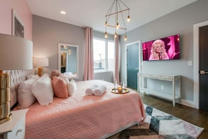 A modern bedroom with a large bed, a TV, and a console table. - Fall Nashville getaway: 2 rooftop homes, karaoke rooms, sleeps 24 (Nashville)
