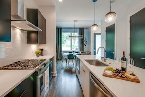 A modern kitchen with a central island, stainless steel appliances, and a dining area with a view.