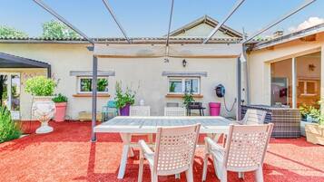 A covered patio with a table and chairs, potted plants, and a pergola structure.
