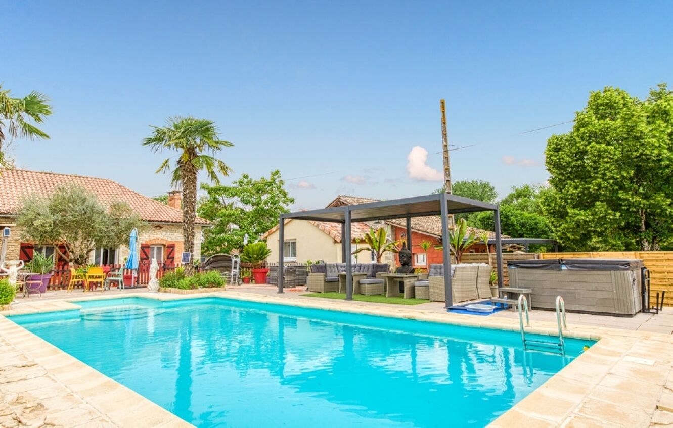 Una piscina amb gandules i una zona d'estar coberta.