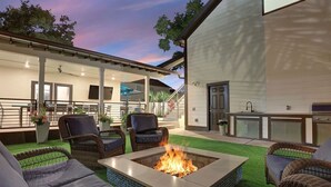 Een terras met rieten meubilair, een vuurkorf en een buitenkeuken.