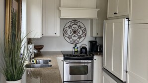 Een keuken met witte kasten, een roestvrijstalen fornuis en een hangende lamp.
