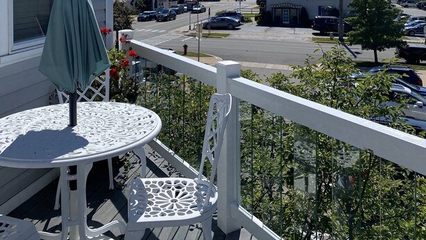 Een balkon met een tafel en stoelen, met uitzicht op een straat met auto's en gebouwen.