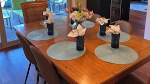 A dining table with placemats, vases with flowers, and a chandelier. - South Beach Dog-friendly Waterfront Villa (Hilton Head Island)