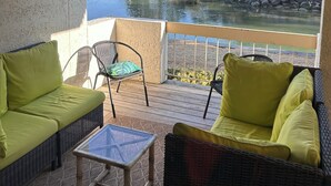 A balcony with wicker furniture, a glass table, and a view of a lake and trees. - South Beach Dog-friendly Waterfront Villa (Hilton Head Island)
