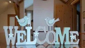 Een receptiegedeelte met een 'WELCOME' bord en een houten decoratie van een scheepsschijf.