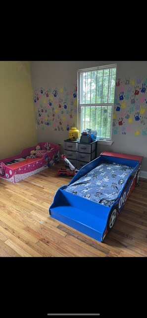 A child's bedroom with a bunk bed, a window, and handprint decorations on the walls.