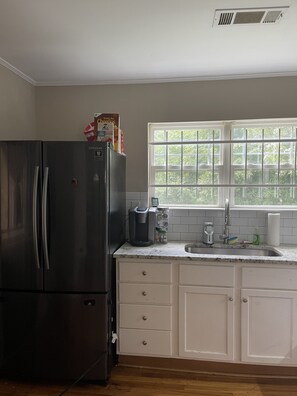 Enjoy a kitchen with a refrigerator, coffee maker, and cabinetry, offering a view of the surrounding greenery.