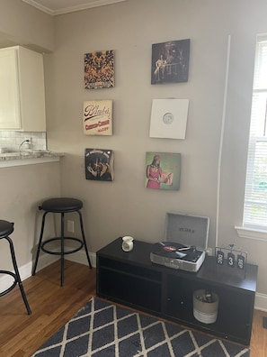 A kitchen with a white countertop, a black stool, a black cabinet, and a black entertainment unit with a vinyl record player.