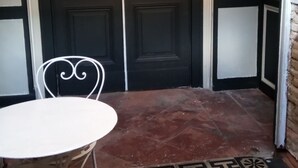A room with a white table and a chair, a patterned floor, and a dark door. - Large bedroom (3 + 1 baby ) & Dining area in a country village -  (Lézat-sur-Lèze)