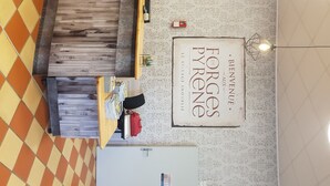 A reception area with a wooden reception desk, a sign reading "Bienvenue Forges Pyrene", and patterned wallpaper. - Large bedroom (3 + 1 baby ) & Dining area in a country village -  (Lézat-sur-Lèze)