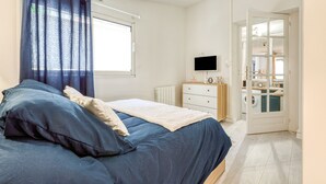 Ein Schlafzimmer mit einem Bett, einem Schminktisch, einem Fernseher und einer Tür zu einem Badezimmer.