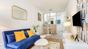 Ein modernes Wohnzimmer mit einem blauen Sofa, einem weißen Couchtisch und einem Fernsehgerät auf einem weißen Schrank.