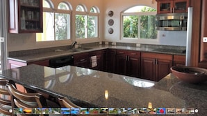 A spacious kitchen with granite countertops, dark wooden cabinets, a large island, and a view of greenery through the windows. - Perfect viewing of migrating Pacific whales, from the hills above Ojochal (Ojochal)